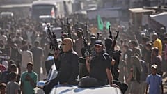  مسلحون من حماس على متن شاحنات صغيرة يرافقون حافلات تقل سجناء فلسطينيين محررين، خان يونس، جنوب قطاع غزة، الاثنين 13 أكتوبر/تشرين الأول 2025. 