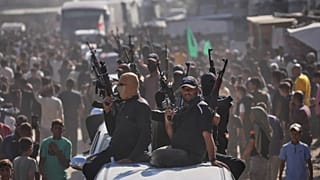  مسلحون من حماس على متن شاحنات صغيرة يرافقون حافلات تقل سجناء فلسطينيين محررين، خان يونس، جنوب قطاع غزة، الاثنين 13 أكتوبر/تشرين الأول 2025. 