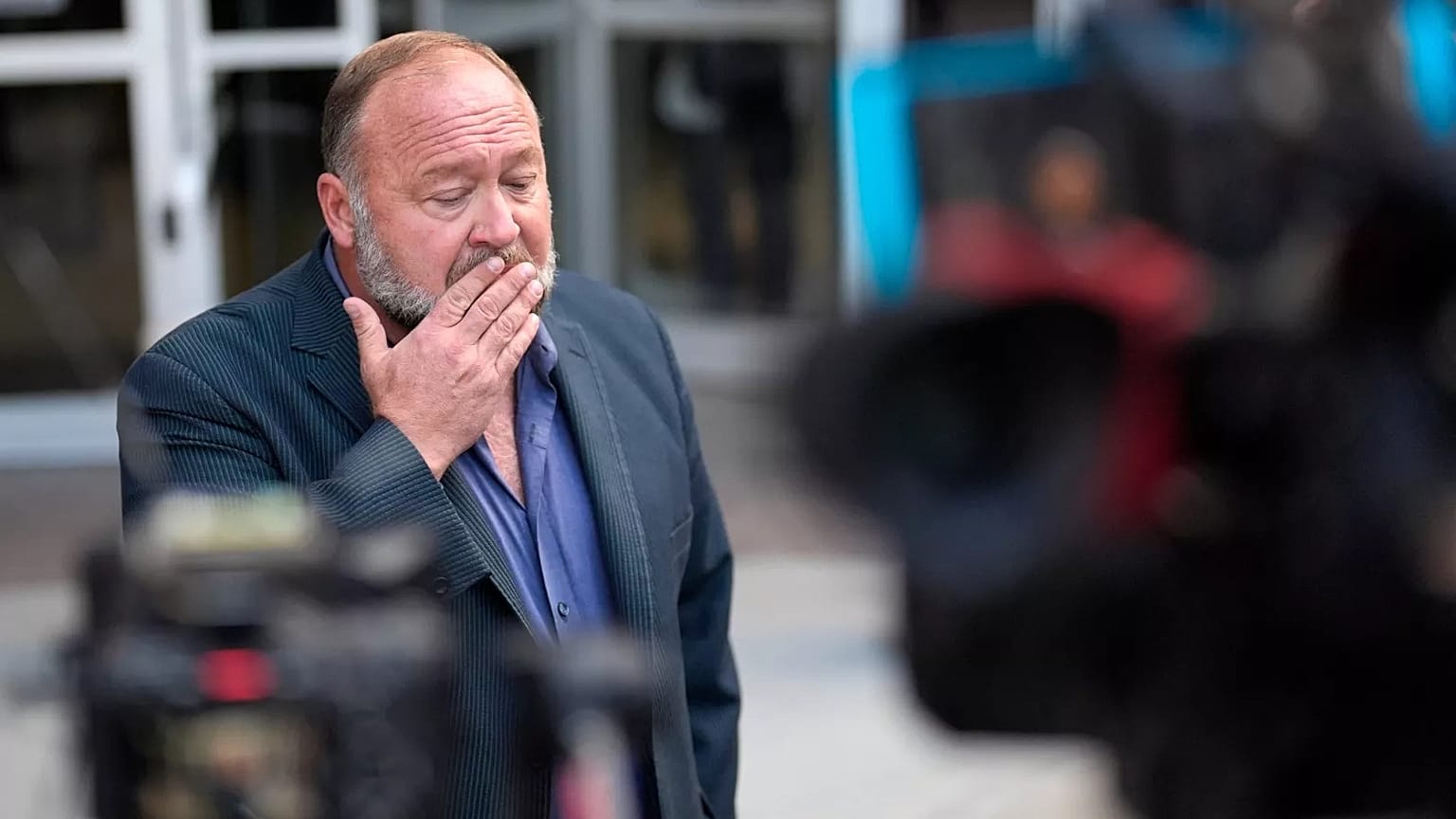Alex Jones pauses before speaking to the media after arriving at the federal courthouse for a hearing in Houston, 14 June, 2024