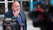 Alex Jones pauses before speaking to the media after arriving at the federal courthouse for a hearing in Houston, 14 June, 2024