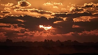 تغيب الشمس خلف المباني المدمرة  في شمال قطاع غزة، كما يُرى من جنوب إسرائيل، الثلاثاء 14 أكتوبر 2025.
