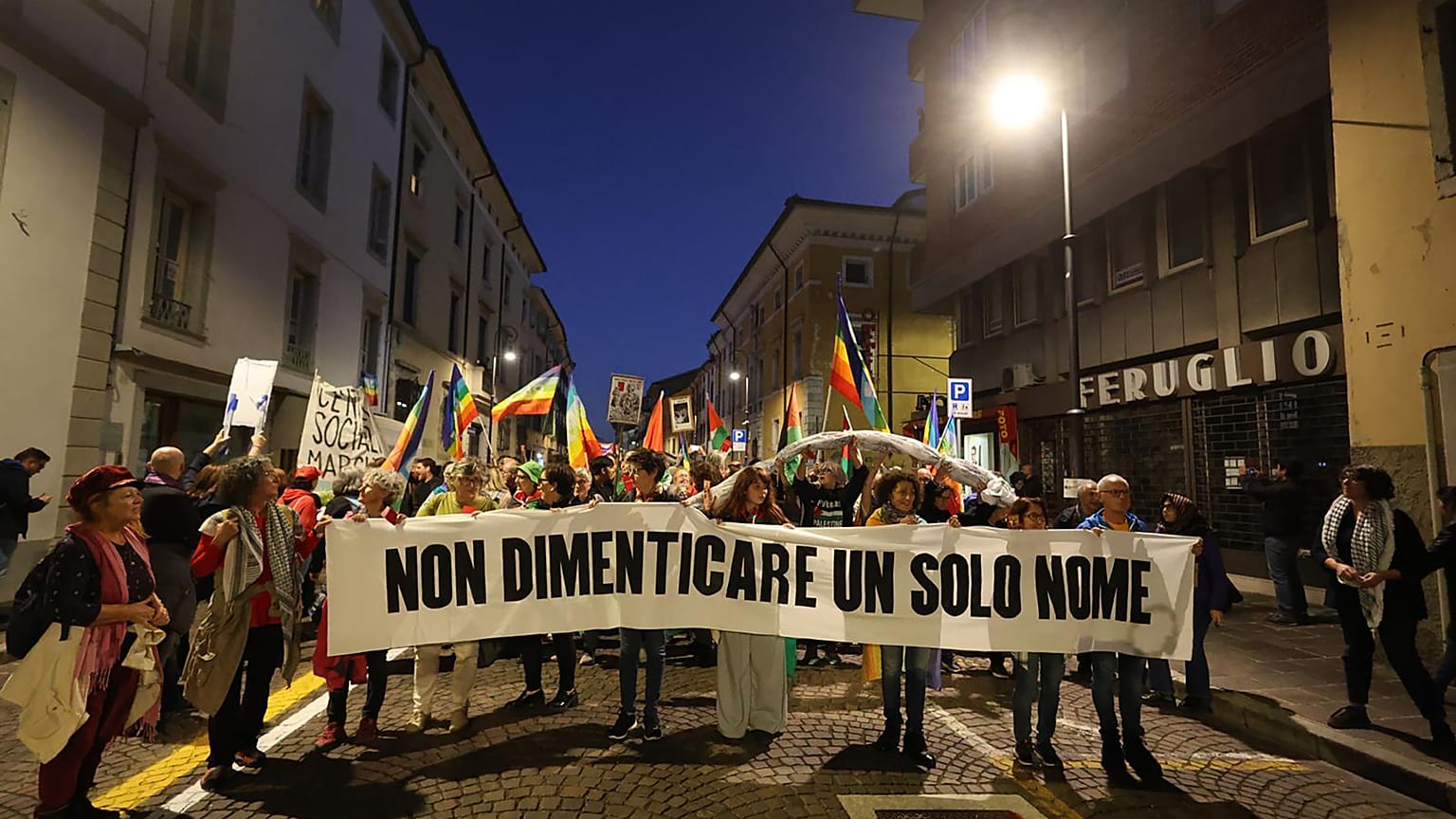 Uczestnicy protestu pro-palestyńskiego trzymają transparent z napisem po włosku: 'Nie zapomnij ani jednego imienia'