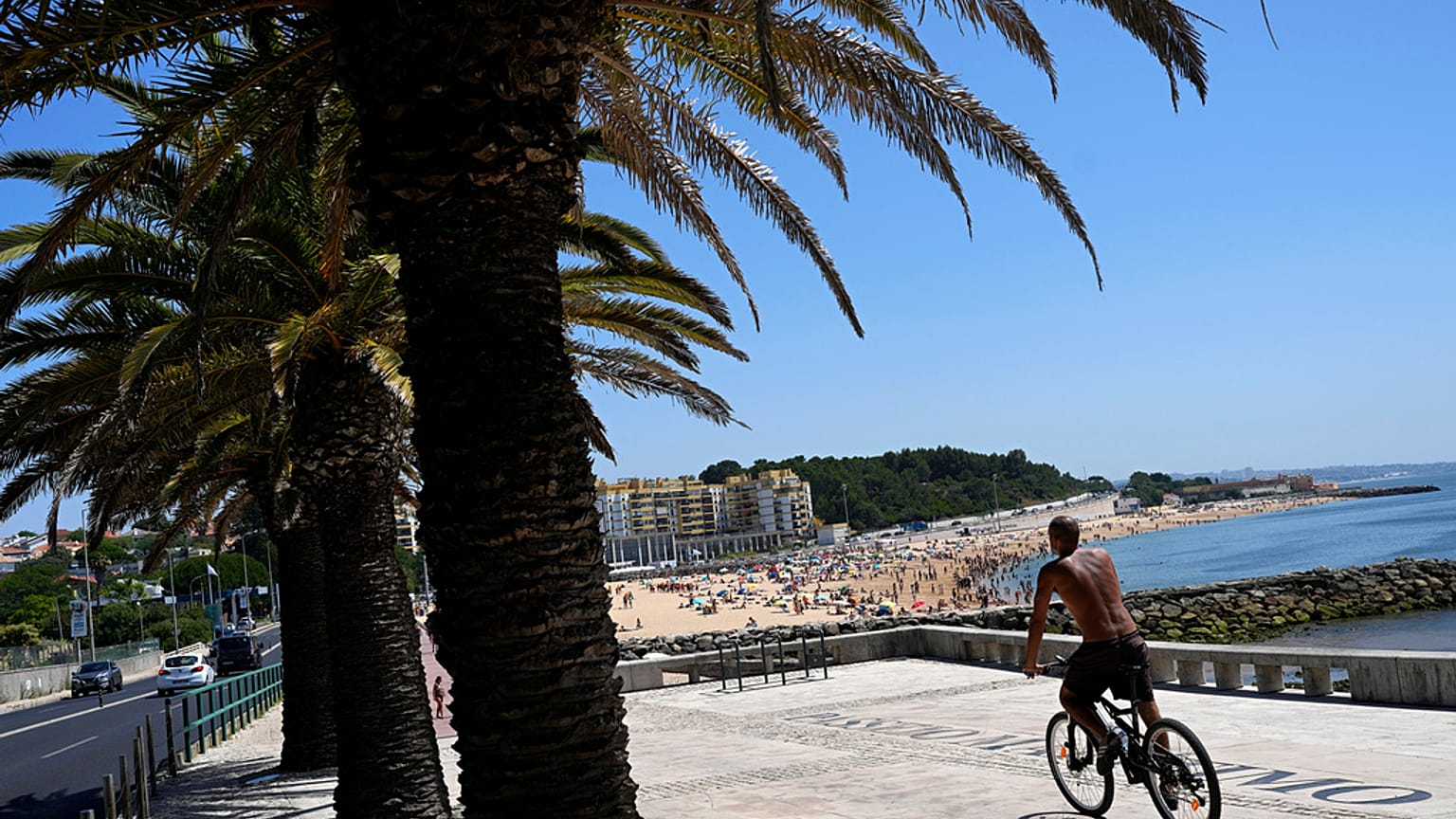 Un homme fait du vélo sur la plage d'Oeiras, dans la banlieue de Lisbonne, le mercredi 19 juillet 2023. 