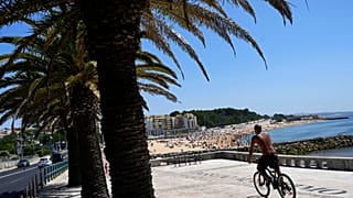 Um homem anda de bicicleta na praia em Oeiras, nos arredores de Lisboa, na quarta-feira, 19 de julho de 2023. 