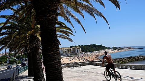 Un homme fait du vélo sur la plage d'Oeiras, dans la banlieue de Lisbonne, le mercredi 19 juillet 2023.