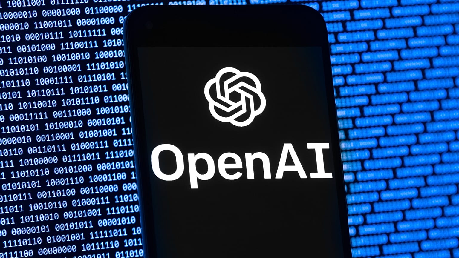 OpenAI logosu, 9 Mart 2023 Perşembe günü Boston'da, rastgele ikili veri içeren bir bilgisayar ekranının önünde bir cep telefonunda görünüyor.