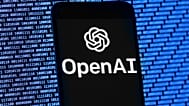 The OpenAI logo appears on a mobile phone in front of a computer screen with random binary data, Thursday, 9 March 2023, in Boston.