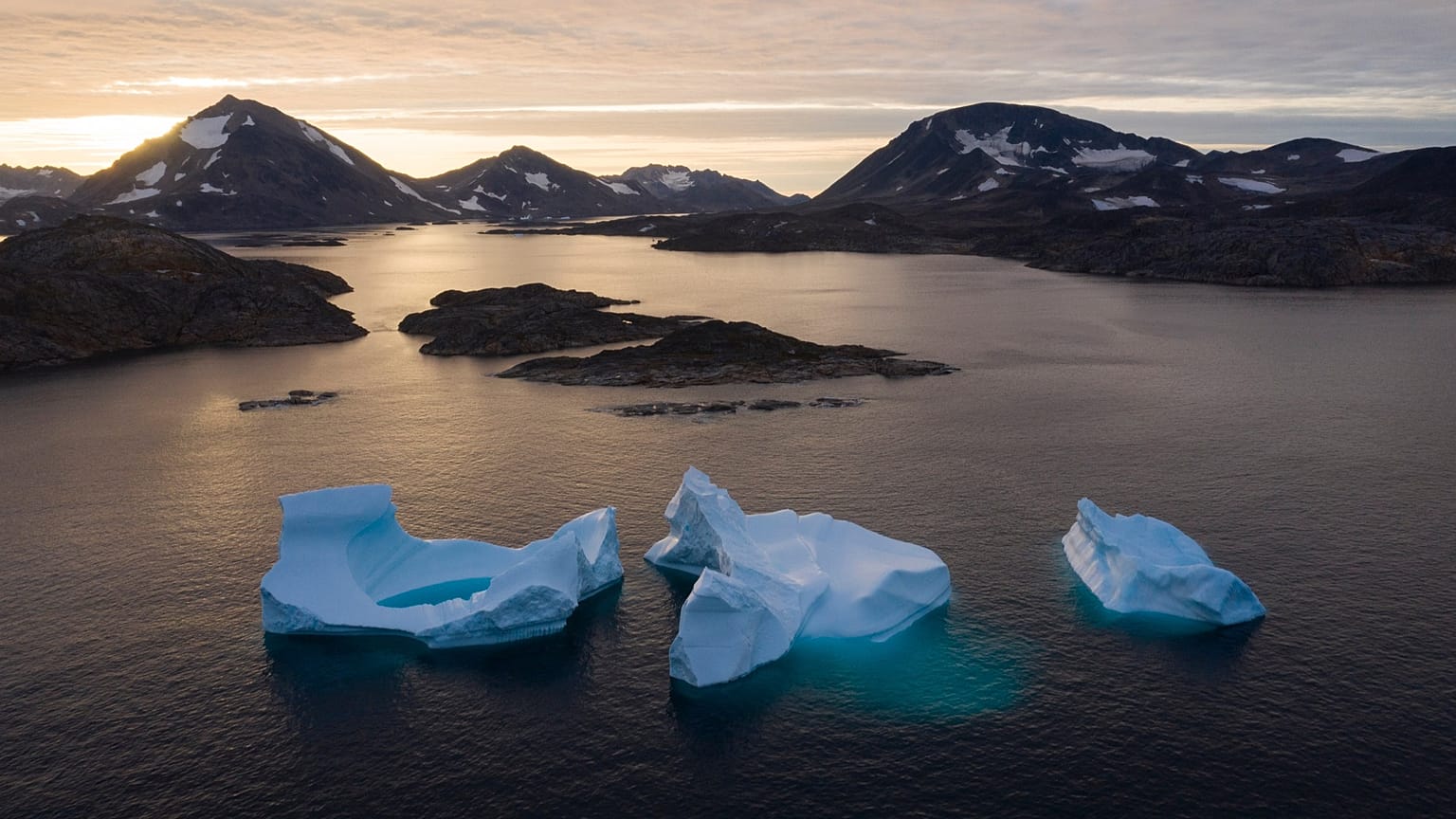 Icebergs float away as the sun rises near Kulusuk, Greenland. 