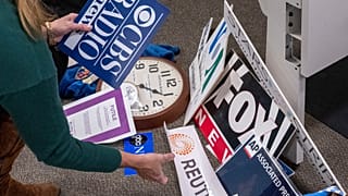 A reporter saves the name plaques from various news outlets as she and members of the media pack up their belongings in the press area in the Pentagon, 15 October 2025