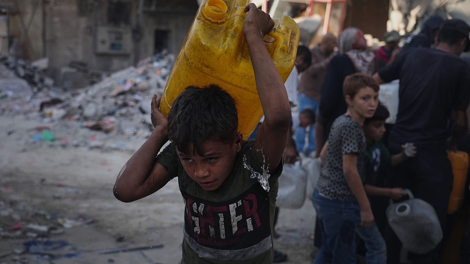 فلسطينيون يحملون عبوات مياه بعد جمعها من شاحنة في مدينة غزة، الخميس 16 أكتوبر/تشرين الأول 2025.