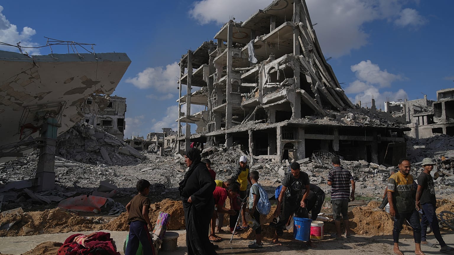 الفلسطينيون يجمعون المياه من أنبوب مكسور وسط المباني المدمرة في مدينة غزة بعد أن اتفقت إسرائيل وحماس على وقف مؤقت للحرب وإطلاق سراح الرهائن المتبقين. (تصوير: أسامة الشريف )