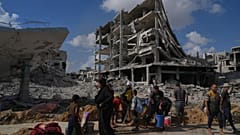 الفلسطينيون يجمعون المياه من أنبوب مكسور وسط المباني المدمرة في مدينة غزة بعد أن اتفقت إسرائيل وحماس على وقف مؤقت للحرب وإطلاق سراح الرهائن المتبقين. (تصوير: أسامة الشريف )