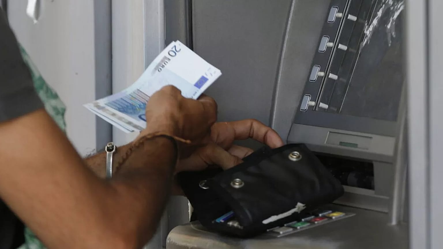 FILE: A man uses an ATM of a bank in Athens, 7 July 2015 