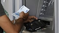 FILE: A man uses an ATM of a bank in Athens, 7 July 2015 