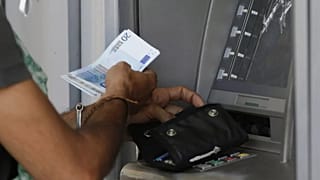FILE: A man uses an ATM of a bank in Athens, 7 July 2015 