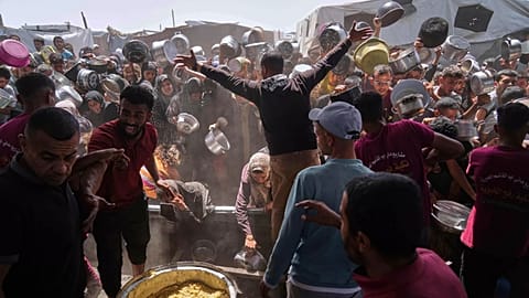 People struggle to get donated food at a community kitchen in Khan Younis, 16 May, 2025