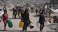 فلسطينيون يحملون عبوات بلاستيكية لجمع المياه من شاحنة وسط الدمار الذي أحدثه الهجوم الجوي والبري الإسرائيلي على مدينة غزة، الخميس 16 أكتوبر 2025. 
