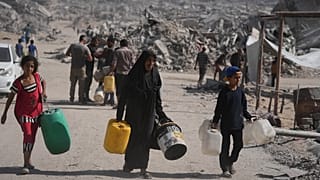 فلسطينيون يحملون عبوات بلاستيكية لجمع المياه من شاحنة وسط الدمار الذي أحدثه الهجوم الجوي والبري الإسرائيلي على مدينة غزة، الخميس 16 أكتوبر 2025. 