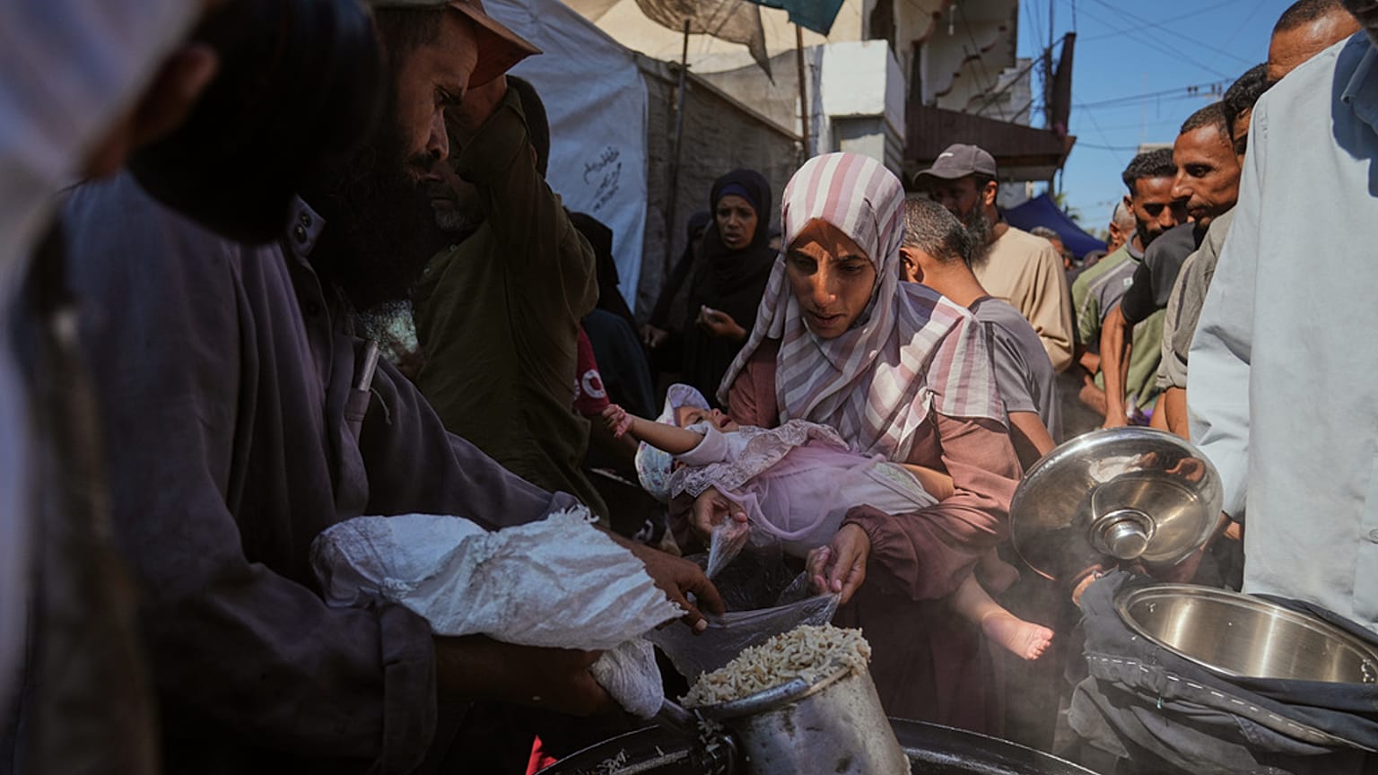  فلسطينيون يتلقون الطعام المتبرع به في مطبخ مجتمعي في دير البلح، وسط قطاع غزة، الخميس 16 أكتوبر/تشرين الأول 2025.