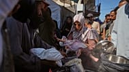  فلسطينيون يتلقون الطعام المتبرع به في مطبخ مجتمعي في دير البلح، وسط قطاع غزة، الخميس 16 أكتوبر/تشرين الأول 2025.