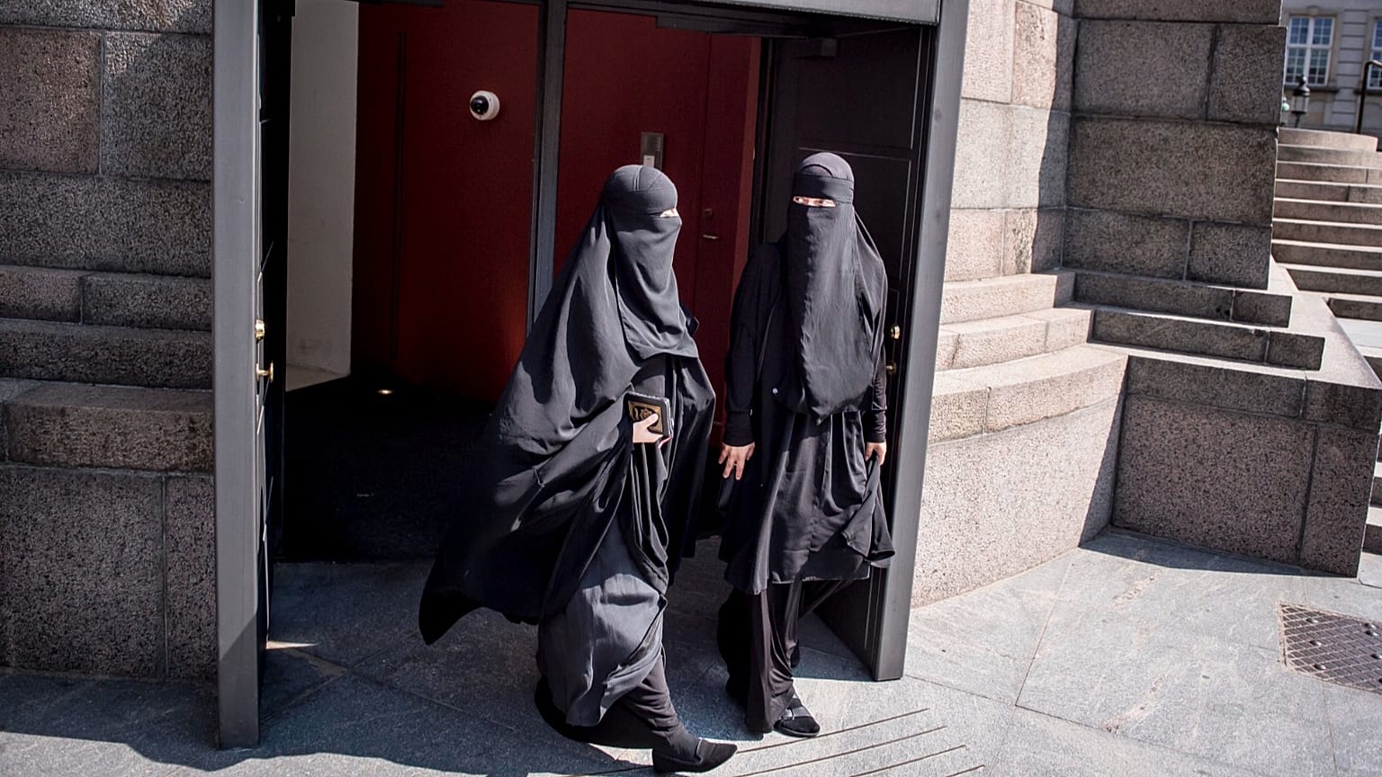 File: Women wearing the islamic veil niqab walk out of the exit doors of the Danish Parliament, at Christiansborg Castle, in Copenhagen, Denmark, Thursday May 31. 2018. 
