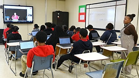 كيتلين بيركنز، معلمة افتراضية (على الشاشة على اليسار)، والمعلمة تامي روكر لمادة الإنجليزية للصف التاسع (على اليمين) خلال الحصة في مدرسة يازو سيتي الثانوية