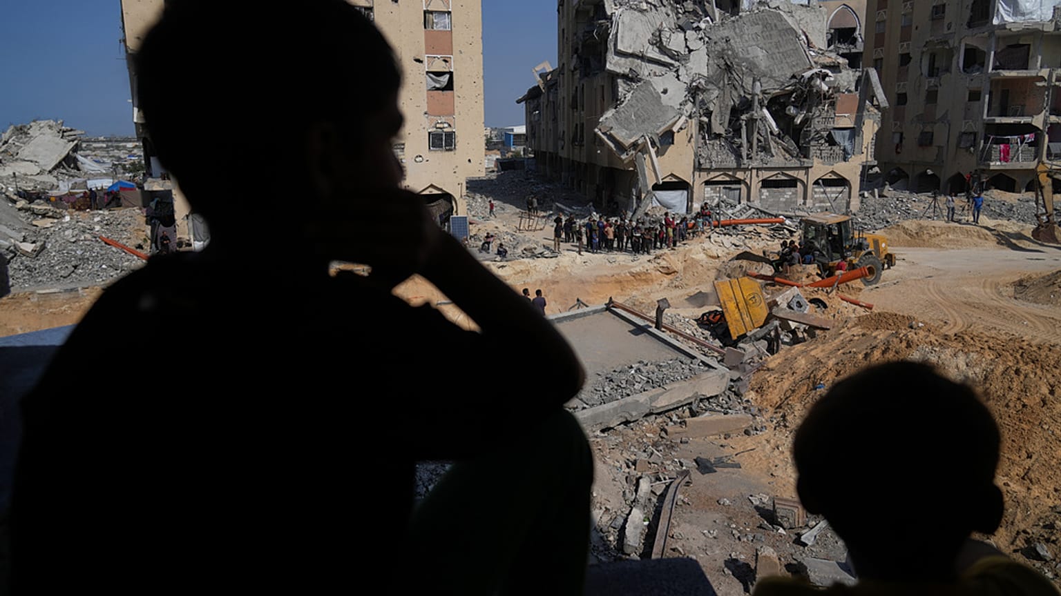فلسطينيون يشاهدون أعضاء حركة حماس وهم يبحثون عن جثث الرهائن في منطقة بمدينة حمد، خان يونس، جنوب قطاع غزة، الجمعة 17 أكتوبر 2025.