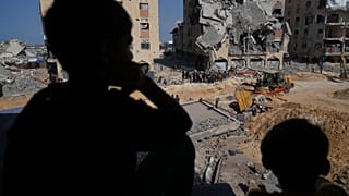 فلسطينيون يشاهدون أعضاء حركة حماس وهم يبحثون عن جثث الرهائن في منطقة بمدينة حمد، خان يونس، جنوب قطاع غزة، الجمعة 17 أكتوبر 2025.