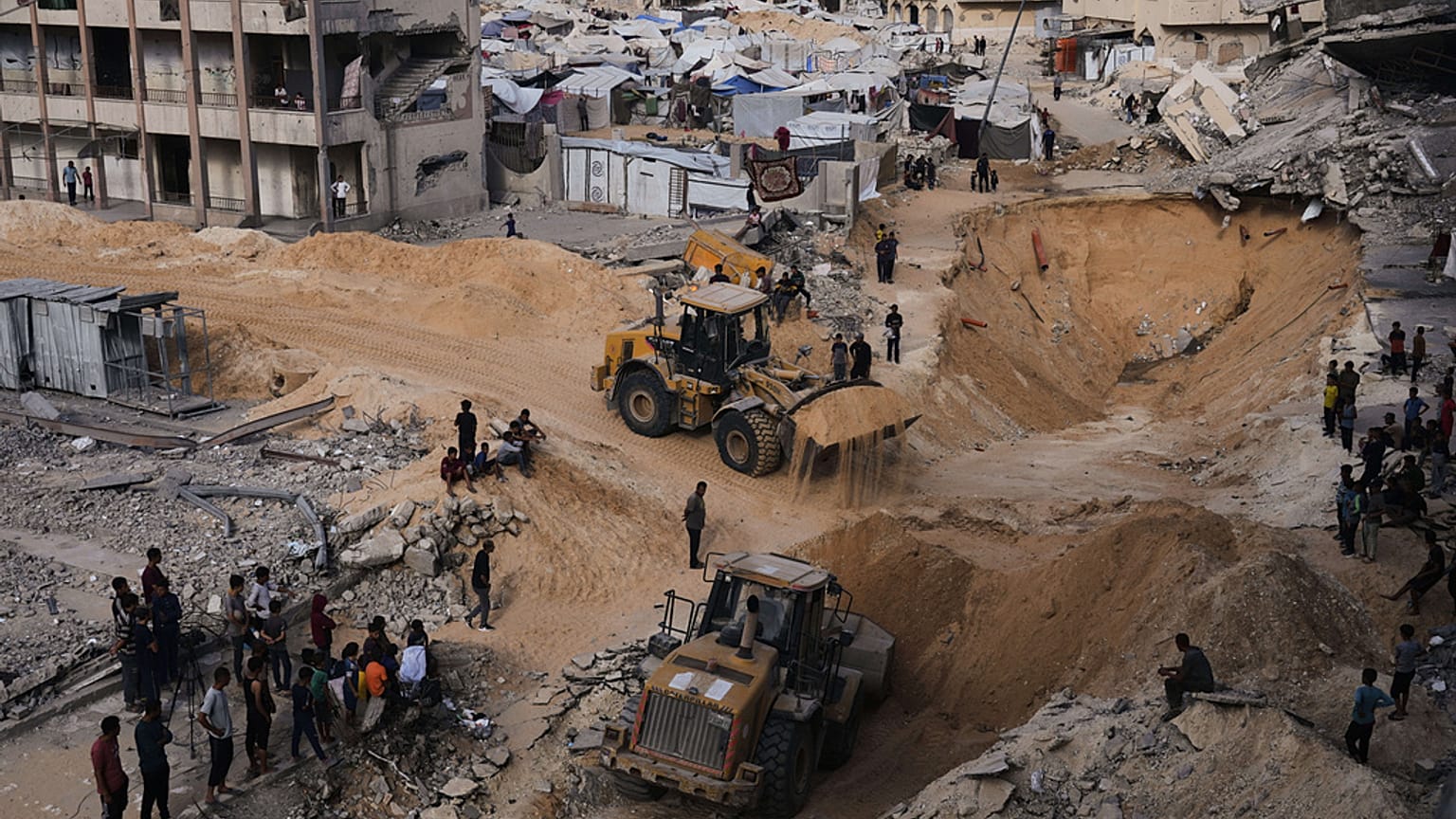 Des Palestiniens observent des membres du groupe militant Hamas chercher les corps des otages dans une zone de la ville de Hamad, Khan Younis, dans le sud de la bande de Gaza, le 18 octobre 2025.