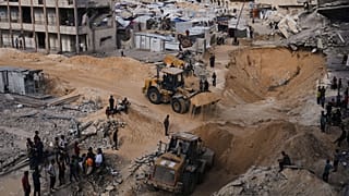 Palästinenser beobachten, wie Mitglieder der militanten Hamas-Gruppe am 18. Oktober 2025 in Hamad City, Khan Younis, im Süden des Gazastreifens nach Geiseln suchen.
