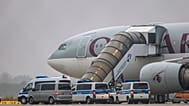 Люди садятся на самолет Qatar Airways, перед которым стоят машины федеральной полиции, на взлетной полосе аэропорта Лейпциг/Галле, пятница, 18 июля 2025 года, Саксония, Шкойдитц.