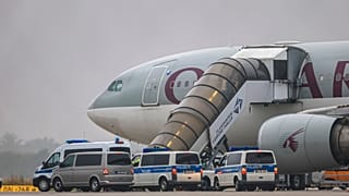 Menschen steigen in ein Flugzeug von Qatar Airways, mit Fahrzeugen der Bundespolizei davor, auf dem Vorfeld des Flughafens Leipzig/Halle, Freitag, 18. Juli 2025, Sachsen, Schkeuditz.