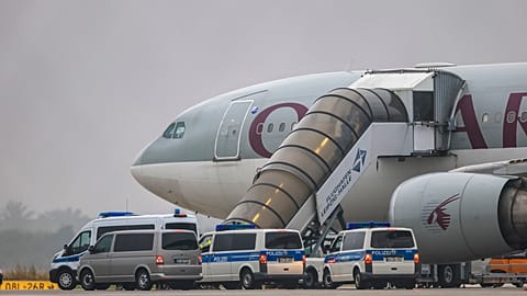 People board a Qatar Airways plane, with federal police vehicles in front of it, on the apron at Leipzig/Halle Airport, Friday, July 18, 2025, Saxony, Schkeuditz.