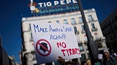 Un manifestant tient une pancarte lors d'une manifestation anti-Trump, à Madrid, Espagne, le samedi 18 octobre 2025.
