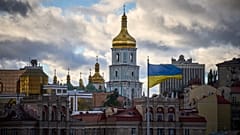 Украинские национальные флаги развеваются на площади Независимости на фоне древнего Софийского собора в центре Киева, Украина, понедельник, 13 октября 2025 года