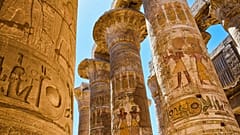 Un grupo de columnas macizas de piedra decoradas con tallas y símbolos