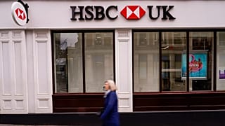 FILE - A person walks past an HSBC branch, in London, 13 March, 2023