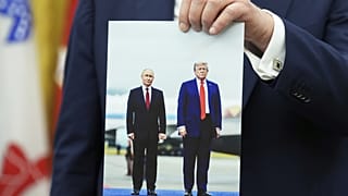 Trump magát és Putyint ábrázoló fotót tart a kezében 