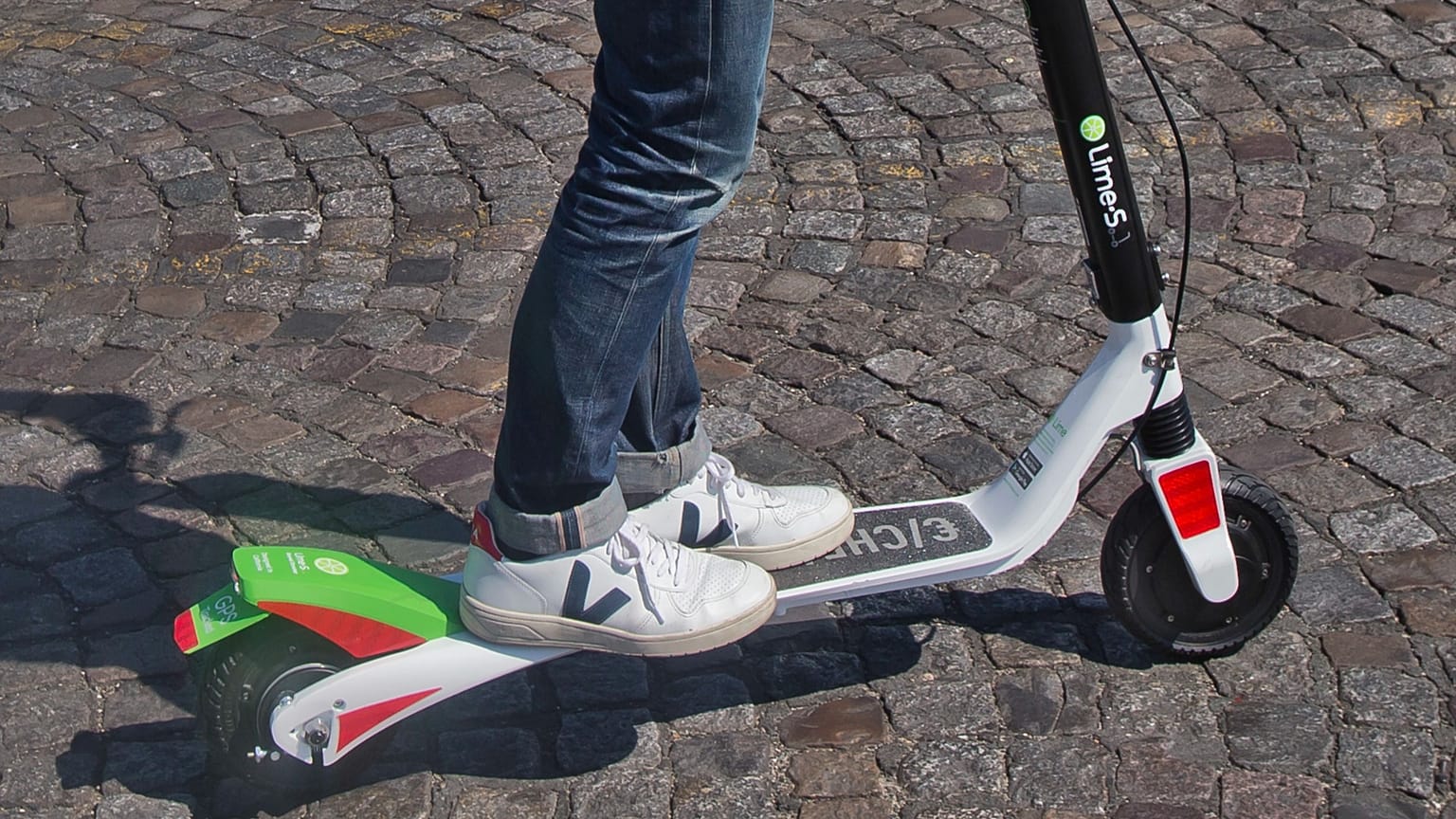 A man stands on a Lime e-scooter in Paris in 2018.