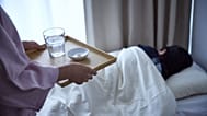 A woman brings medicine to a sick teenager.