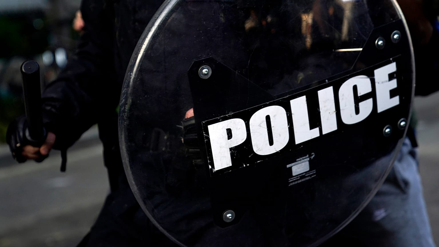 ضابط وهو يحمل هراوة ودرعًا بينما يتجمع المتظاهرون للاحتجاج على وفاة جورج فلويد قرب البيت الأبيض في واشنطن.