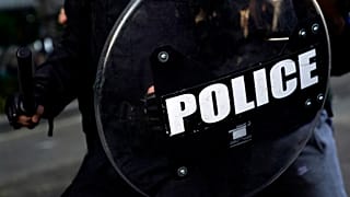 ضابط وهو يحمل هراوة ودرعًا بينما يتجمع المتظاهرون للاحتجاج على وفاة جورج فلويد قرب البيت الأبيض في واشنطن.