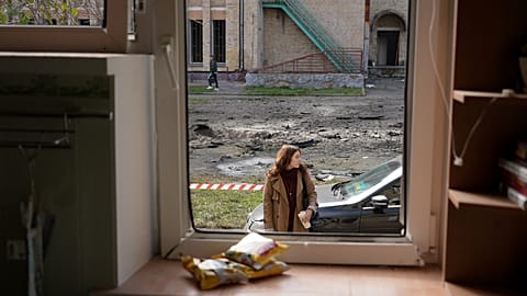 Женщина смотрит на поврежденный жилой дом после атаки российских войск в четверг, 23 октября 2025 года, в районе Подола в Киеве, Украина.