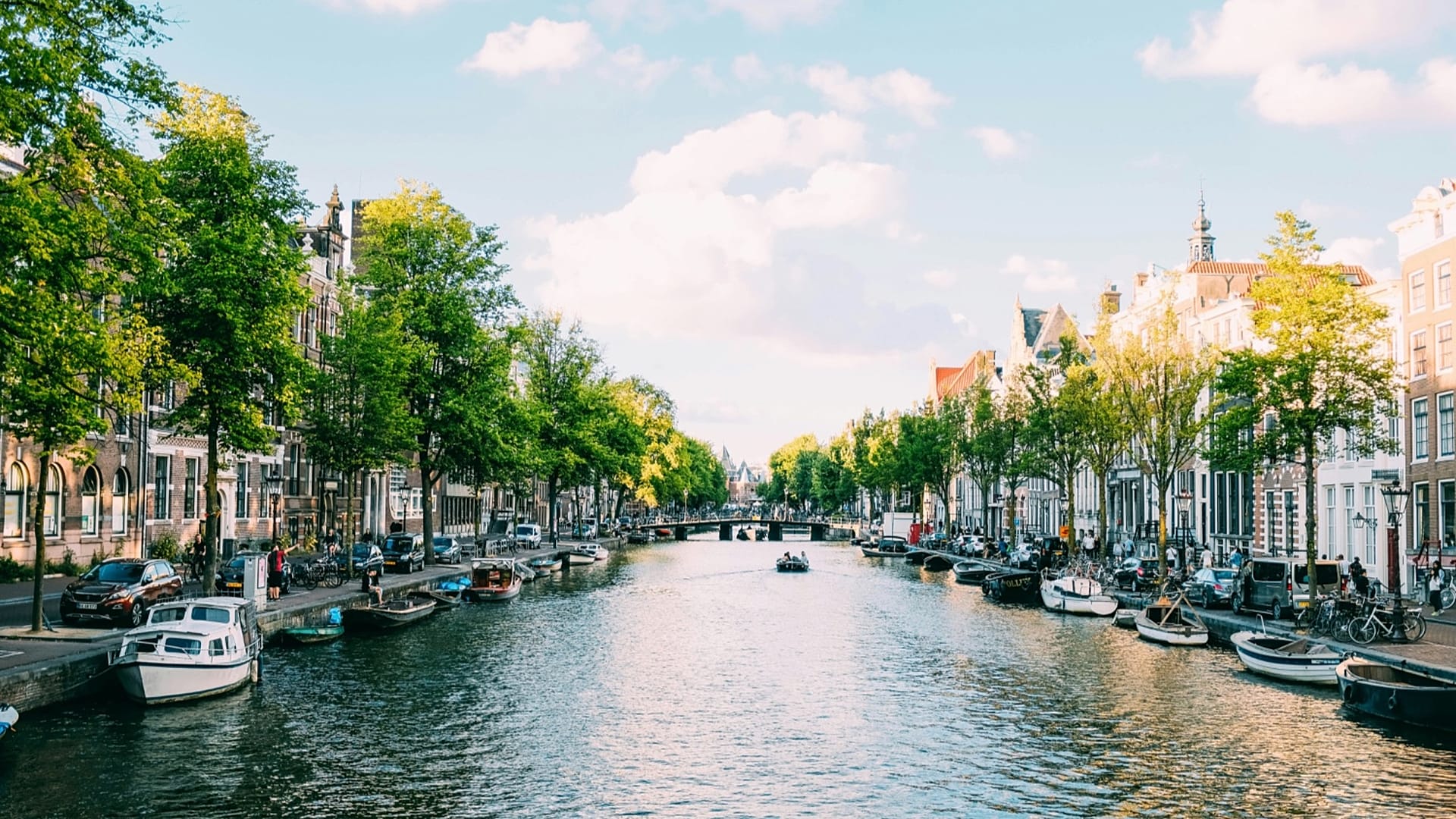 Люди на лодке плывут по каналу в Амстердаме, Нидерланды.