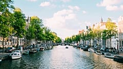 Unas personas navegan en barco por un canal de Ámsterdam, en los Países Bajos.