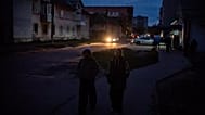 Des enfants marchent dans une rue résidentielle sombre pendant une panne d'électricité à Shostka, le 16 octobre 2025.