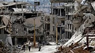 Residents walk through rubble with damaged electricity lines at the mountain resort town of Zabadani, 18 May, 2017