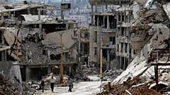 Dağ tatil beldesi Zabadani'de elektrik hatlarının zarar gördüğü moloz yığınları arasında yürüyen bölge sakinleri, 18 Mayıs 2017