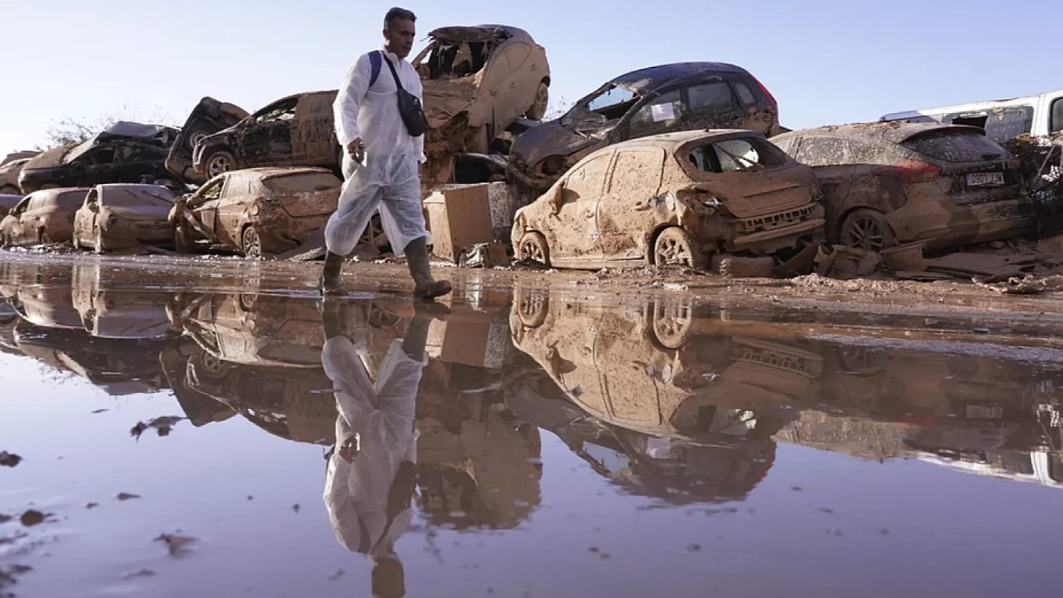 ARCHIVO - Un hombre camina junto a una hilera de coches apilados tras las inundaciones en Catarroja, que dejaron cientos de muertos y desaparecidos en la región valenciana.