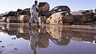 ARCHIVO - Un hombre camina junto a una hilera de coches apilados tras las inundaciones en Catarroja, que dejaron cientos de muertos y desaparecidos en la región valenciana.